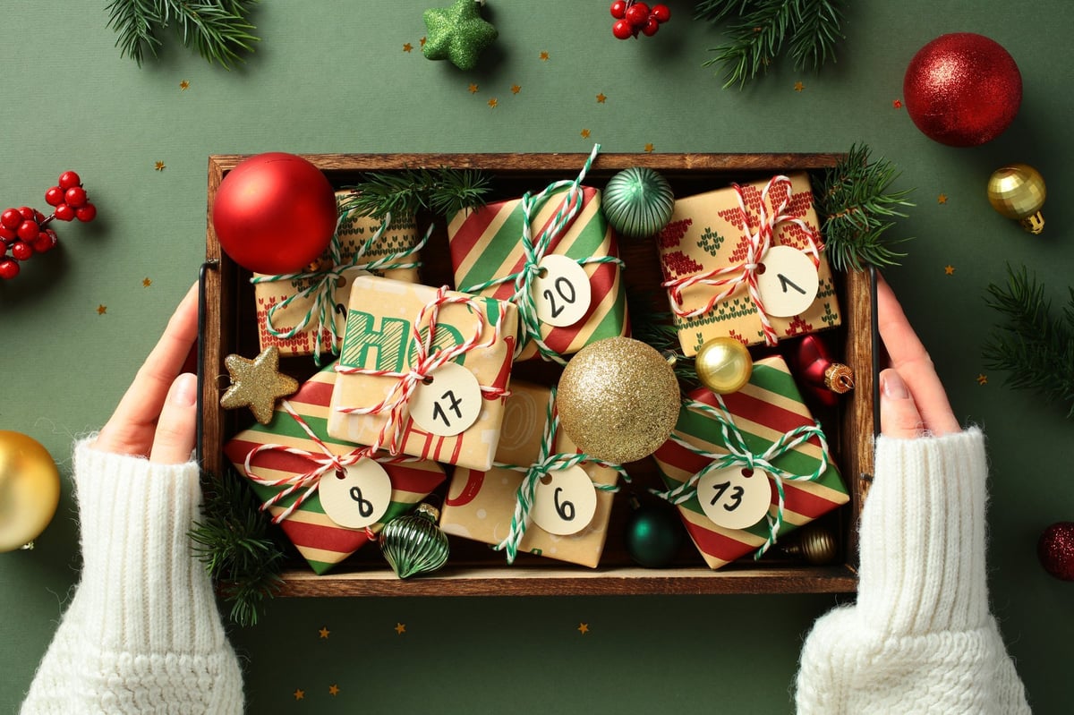 Numbered advent calendar number tags on small gifts in a wooden box