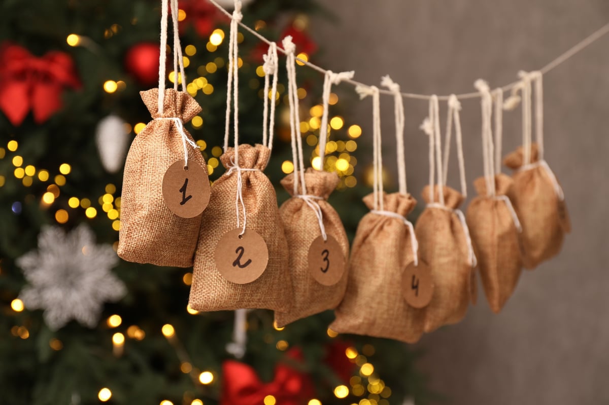 Advent calendar with small gifts hanging beside a Christmas tree indoors